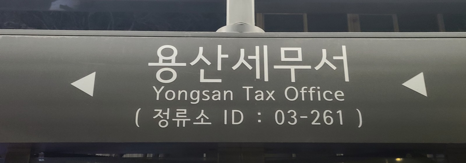 Close view of the stop name board, which reads Yongsan Tax Office in Korean and English with the stop ID 03-261