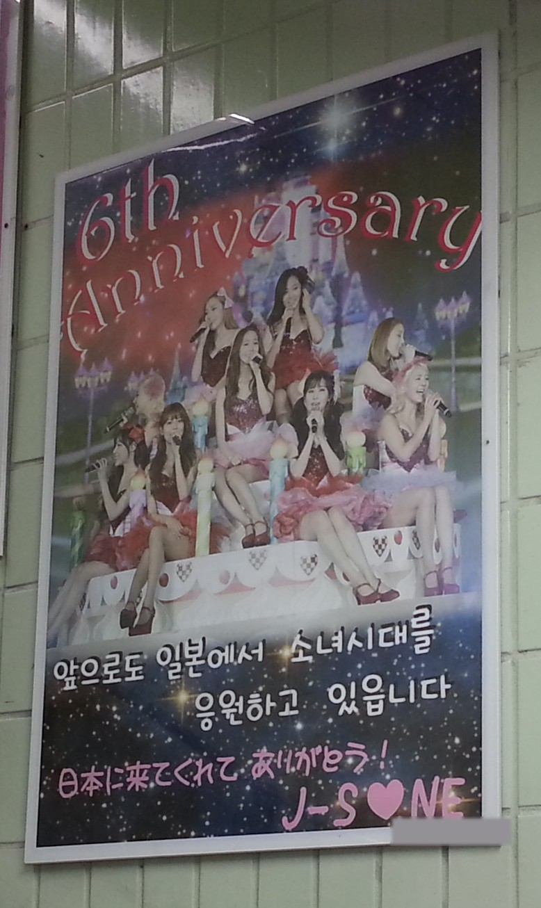 The poster on a green tiled wall beside a station staircase
