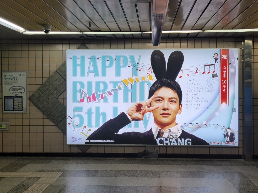 Wider view of the same lightbox on a tiled wall in a Nambu Bus Terminal Station passage, seen from across the floor