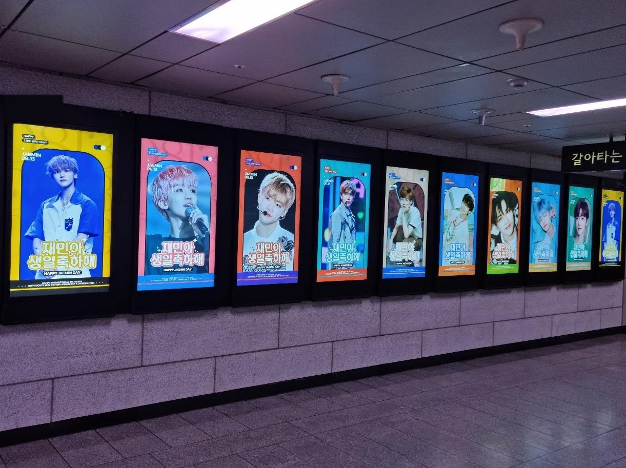 The long row of screens seen from the near end, with a transfer sign above the passage