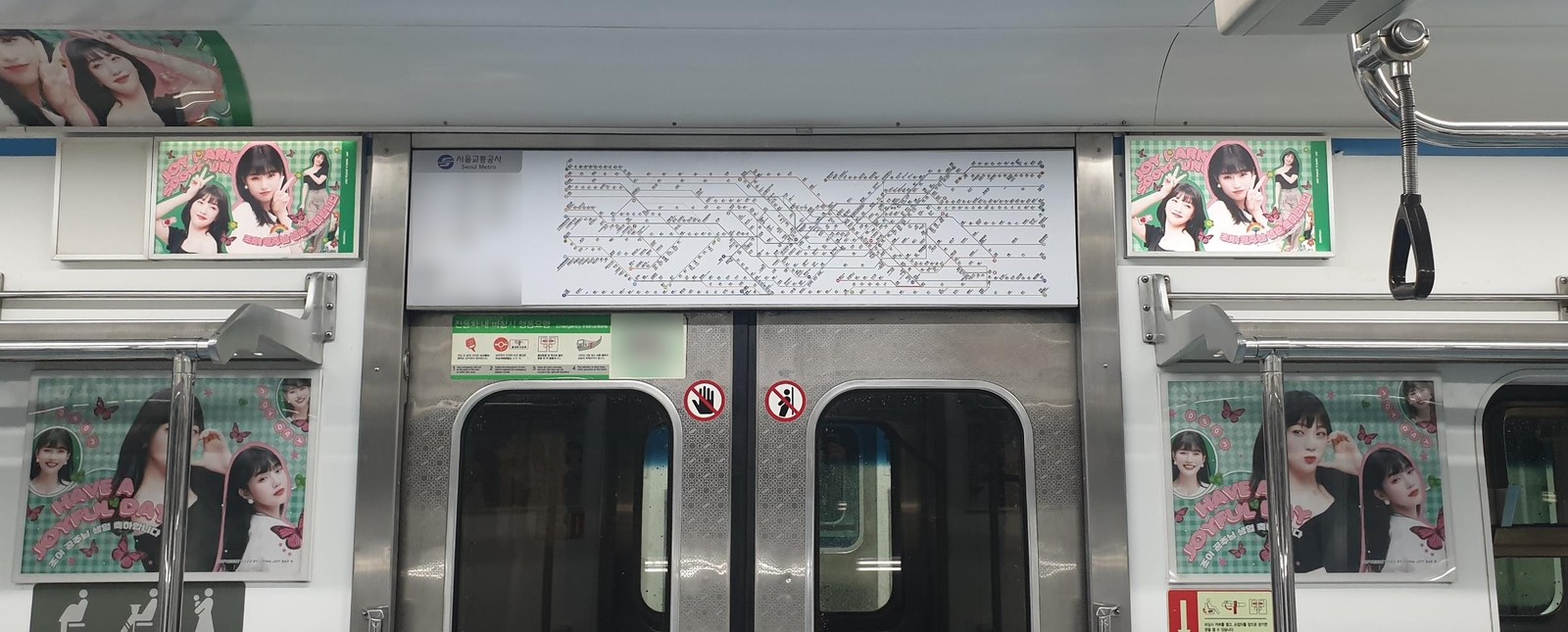 Subway car doors with matching green Joy birthday posters in the frames on both sides