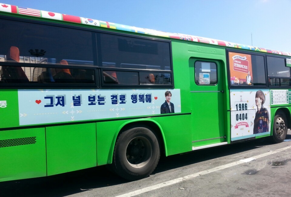 Door side of the same green bus with a banner of Korean text and a panel showing the numbers 1986 and 0404