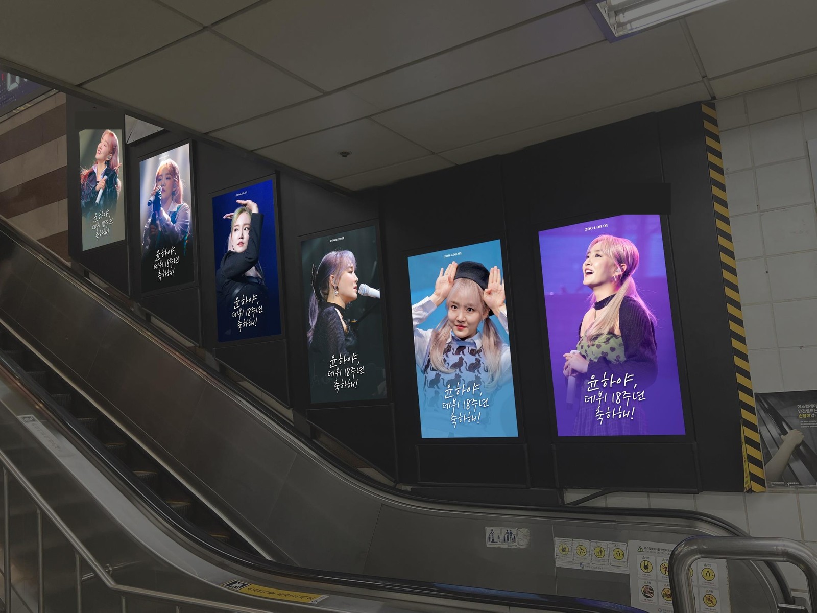 Younha 18th debut anniversary ad on six upright digital screens stepping up the wall beside a subway escalator